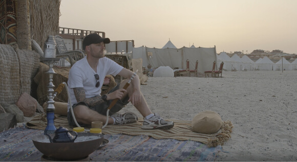 Facet siedzący na pustyni z fajką wodną